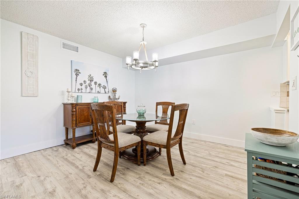 Dining room with light wood finished floors, a textured ceiling, and a chandelier