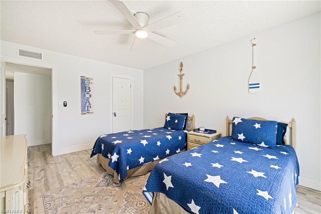 Bedroom with light wood finished floors, a textured ceiling, and a ceiling fan