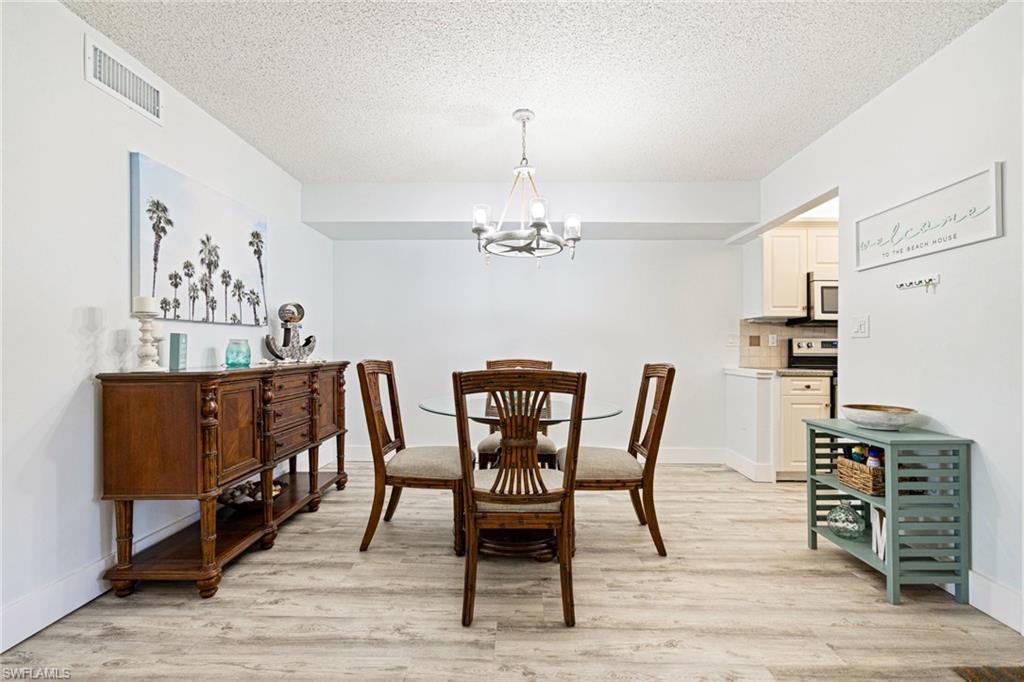 Dining space with a chandelier, light wood-style floors, and a textured ceiling