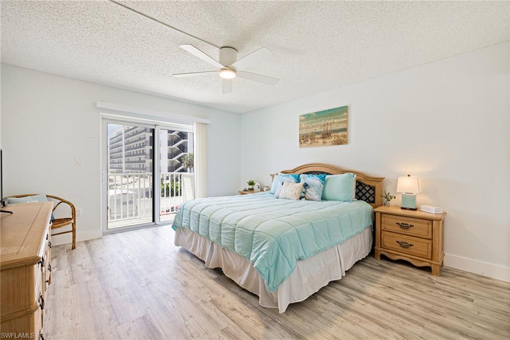 Bedroom featuring a textured ceiling, light wood-style flooring, a ceiling fan, and access to outside