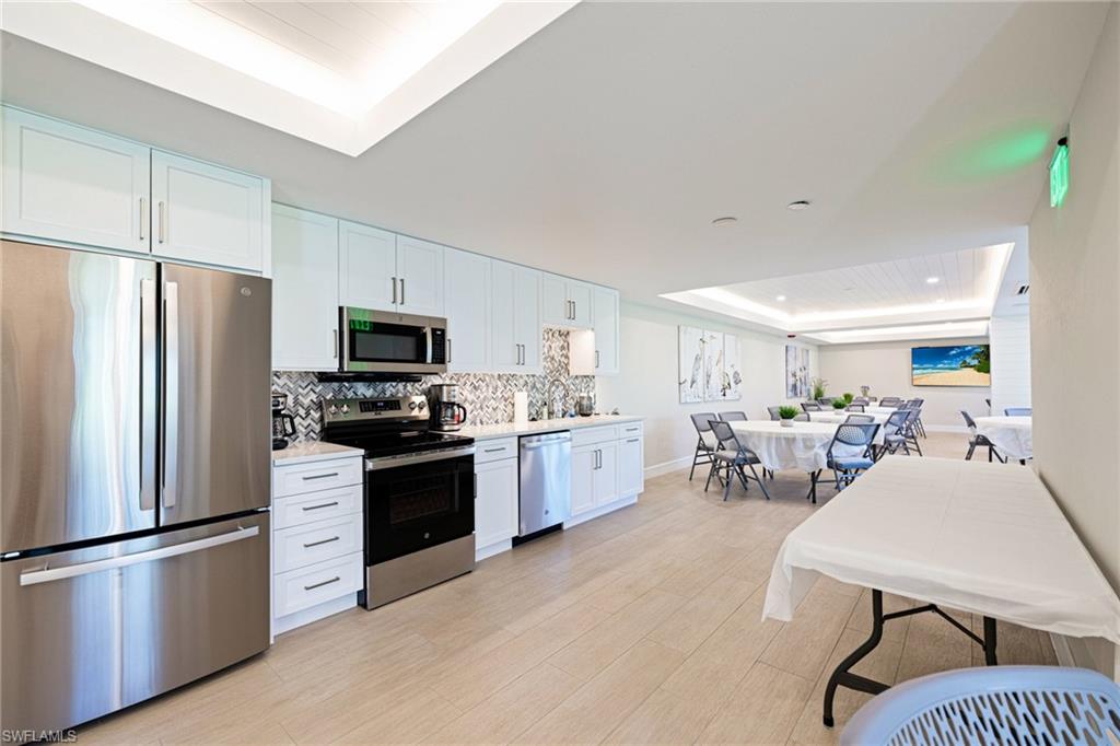 Kitchen featuring a raised ceiling, appliances with stainless steel finishes, white cabinetry, and light wood-type flooring