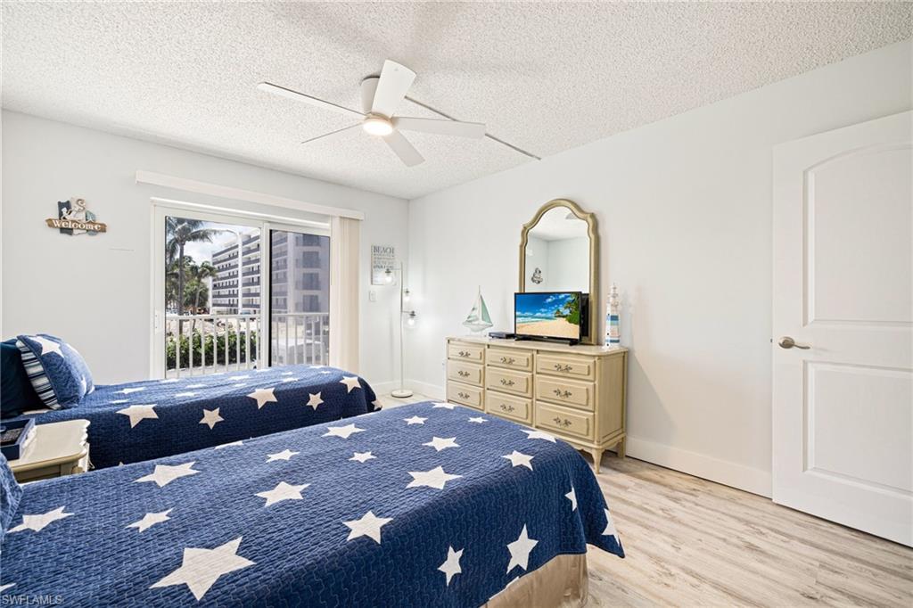 Bedroom featuring a textured ceiling, light wood finished floors, ceiling fan, and access to exterior