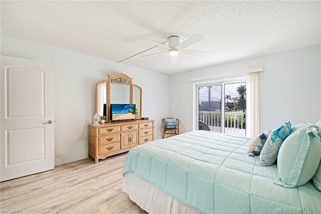 Bedroom featuring a textured ceiling, light wood-type flooring, access to exterior, and a ceiling fan