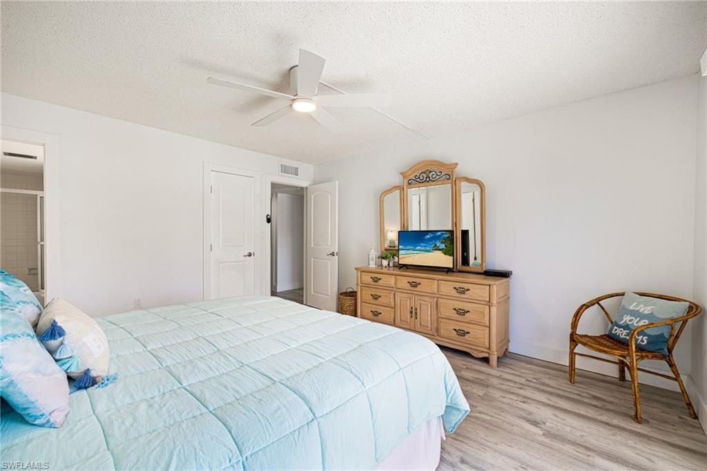 Bedroom with light wood-type flooring, a textured ceiling, and ceiling fan