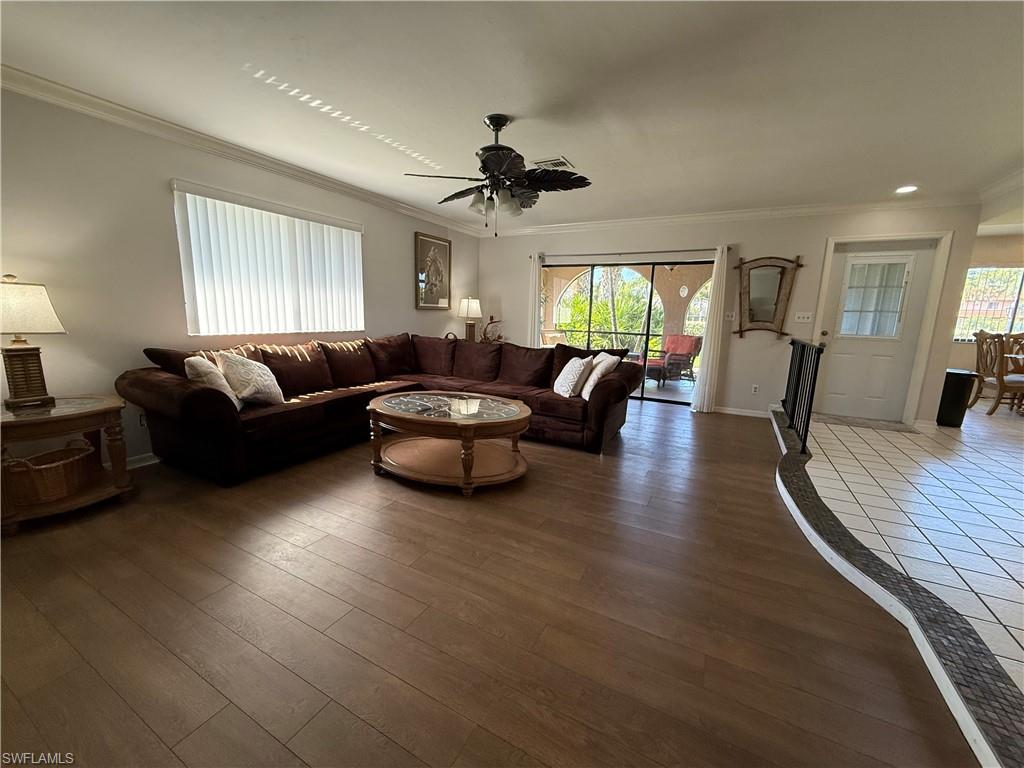Living area featuring crown molding, a ceiling fan, plenty of natural light, and wood finished floors