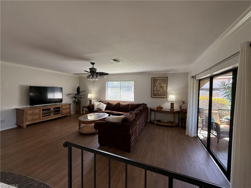 Living area featuring crown molding, dark wood finished floors, and ceiling fan