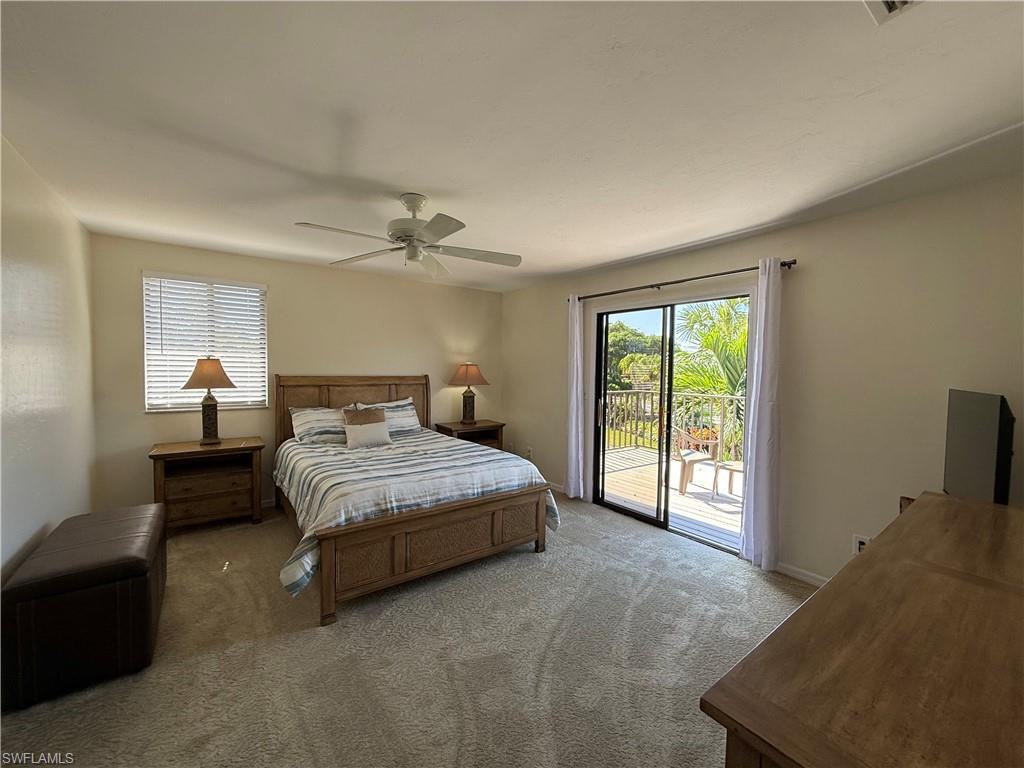 Carpeted bedroom with access to exterior, multiple windows, and a ceiling fan