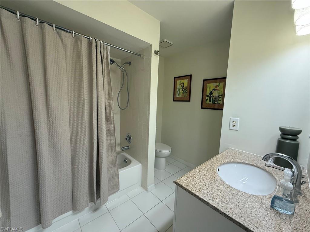 Full bath featuring light tile patterned flooring, vanity, and shower / tub combo with curtain