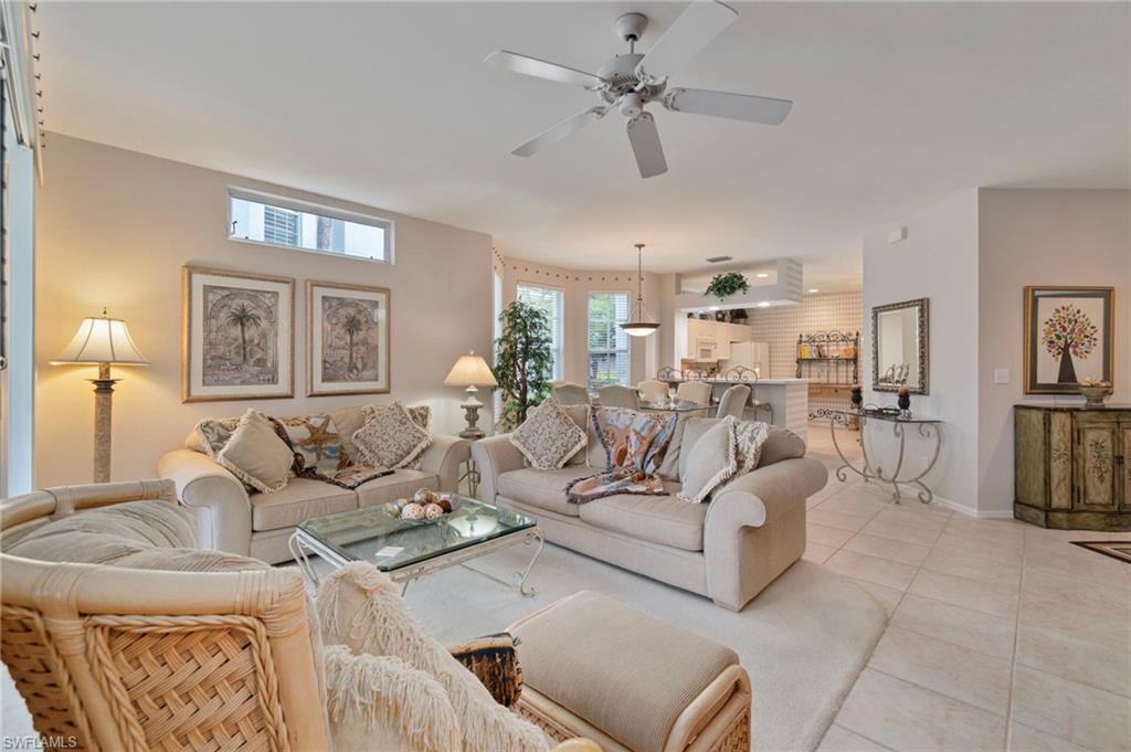 Tiled living room with ceiling fan and baseboards