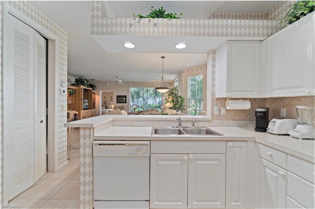 Kitchen featuring light countertops, white dishwasher, decorative backsplash, light tile patterned floors, and open floor plan