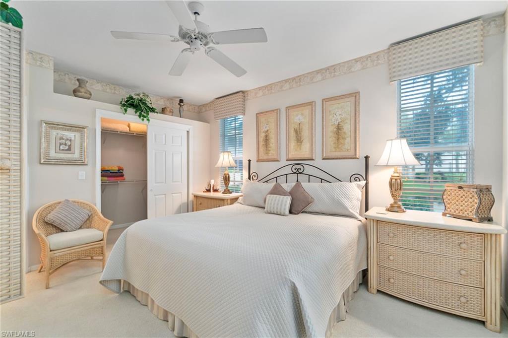 Carpeted bedroom with a spacious closet, multiple windows, and ceiling fan