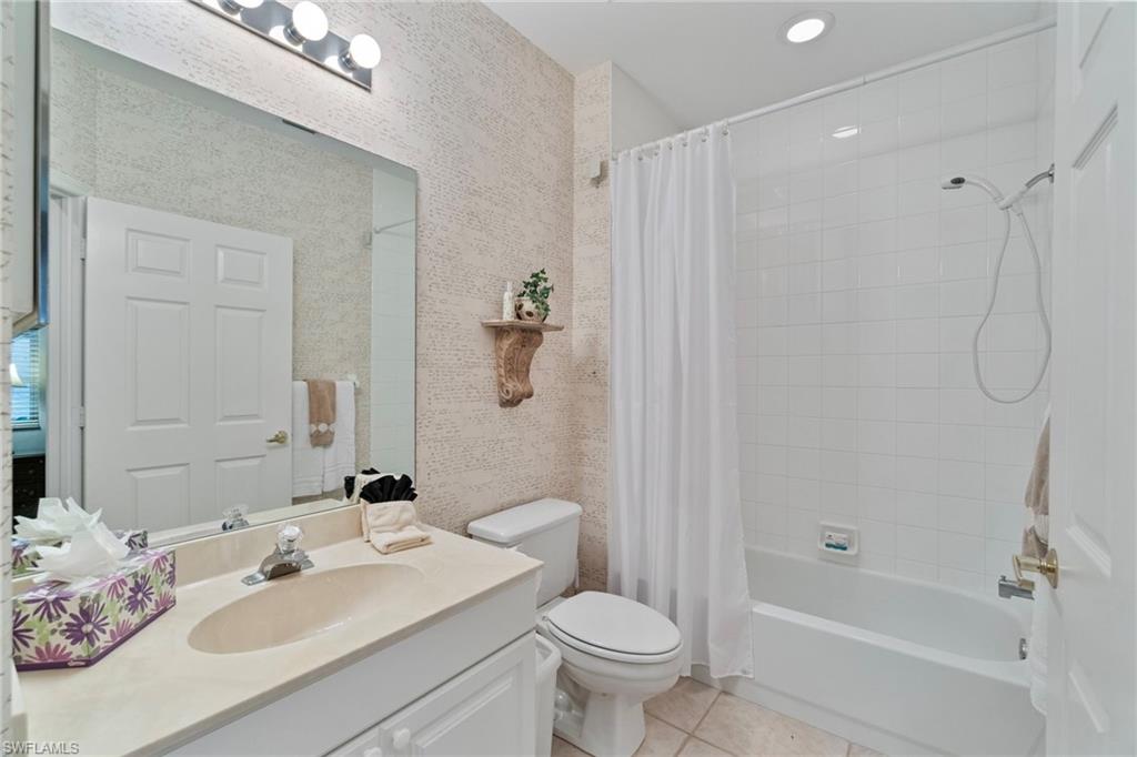 Full bathroom featuring vanity, light tile patterned flooring, shower / bathtub combination with curtain, and wallpapered walls