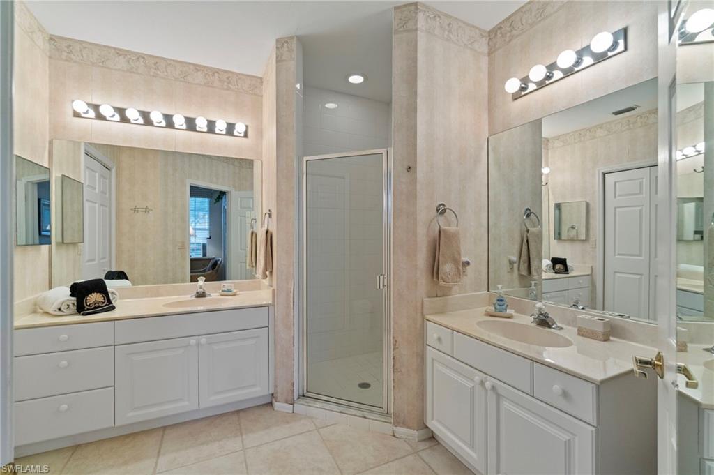 Full bath with light tile patterned floors, a stall shower, two vanities, and recessed lighting
