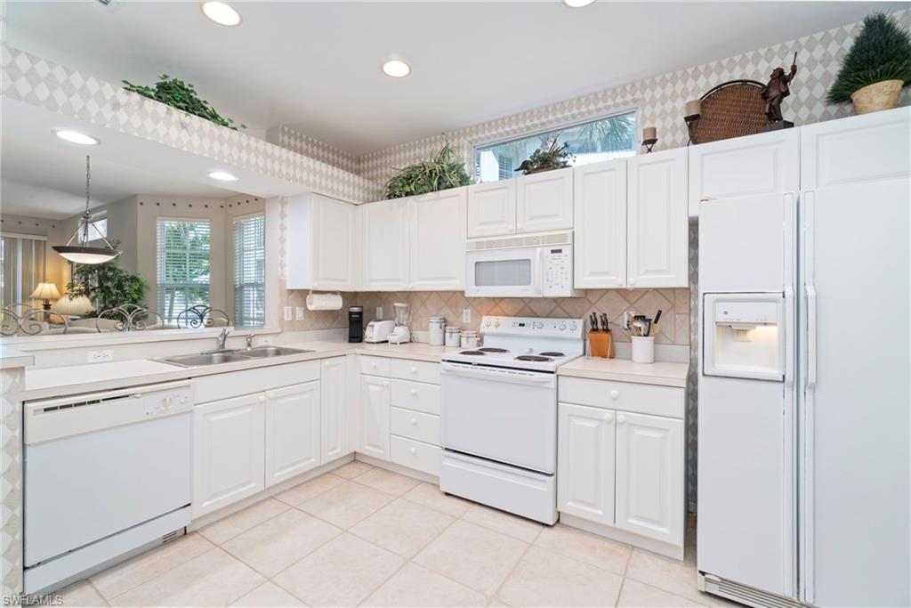 Kitchen with white appliances, decorative backsplash, light countertops, light tile patterned floors, and recessed lighting