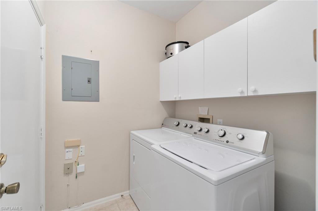 Laundry area with electric panel, cabinet space, separate washer and dryer, and light tile patterned floors