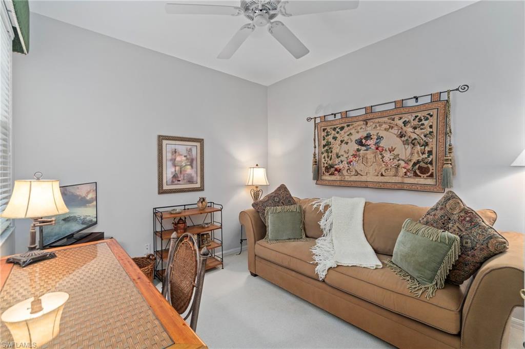 Carpeted home office featuring a ceiling fan