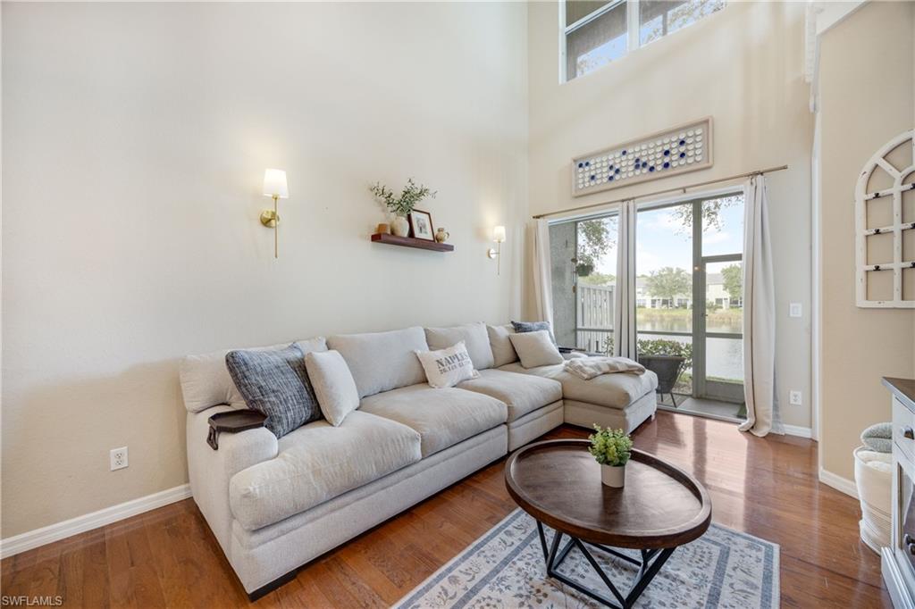 Living room with plenty of natural light, a high ceiling, and wood finished floors