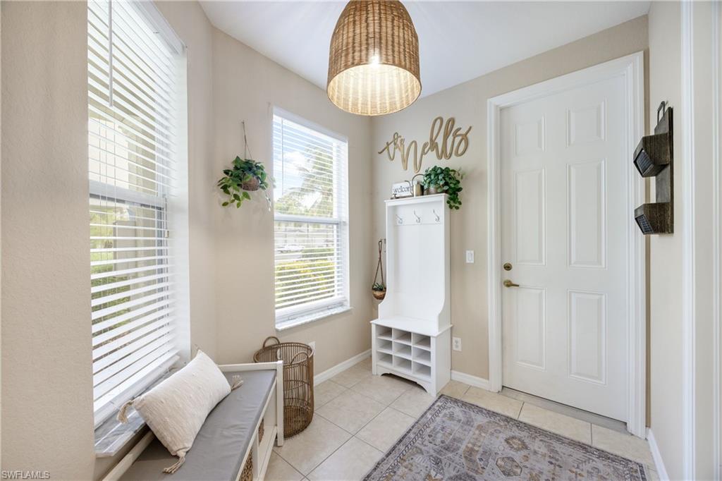 Back entry connected to 2 car garage with light tile patterned floors and baseboards-could be dinette