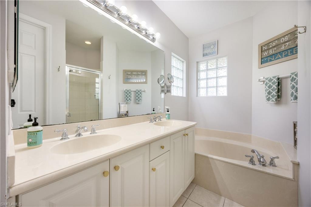 Full bath featuring a stall shower, double vanity, a bath, and light tile patterned floors