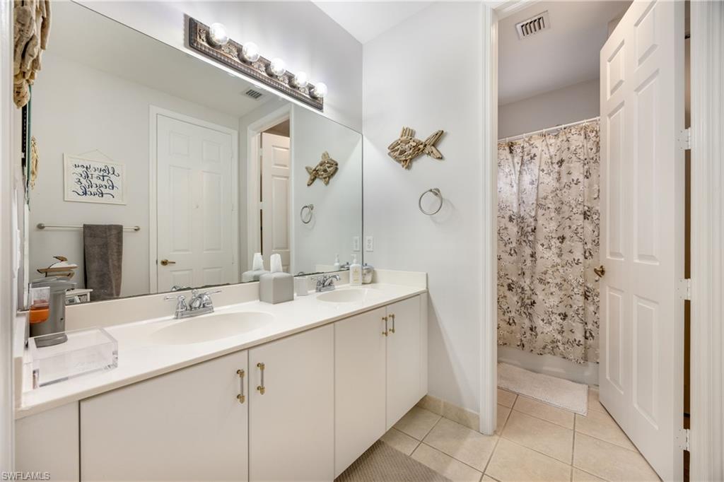 Bathroom with double vanity, a shower with curtain, and light tile patterned flooring