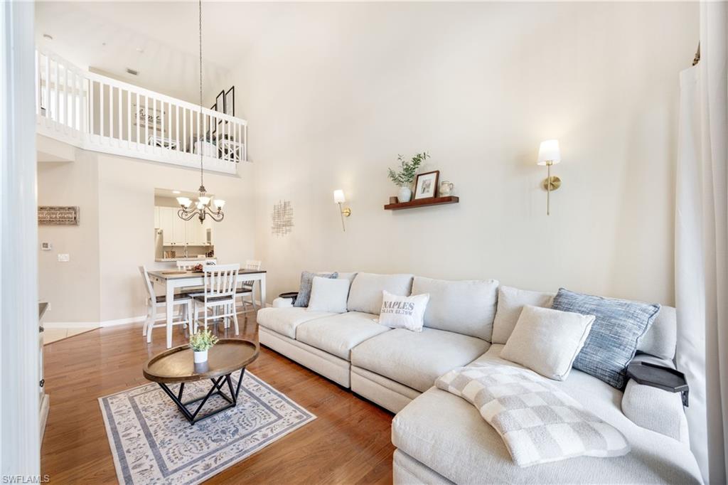Living area featuring a towering ceiling, wood finished floors, and a chandelier