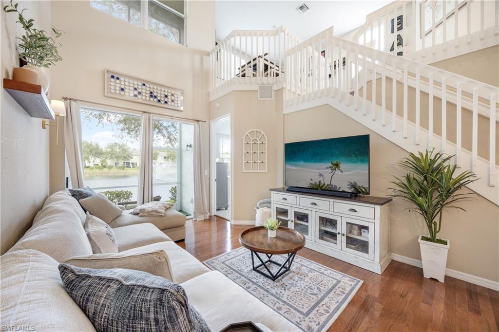 Living room featuring plenty of natural light, stairs, dark wood finished floors, and a high ceiling
