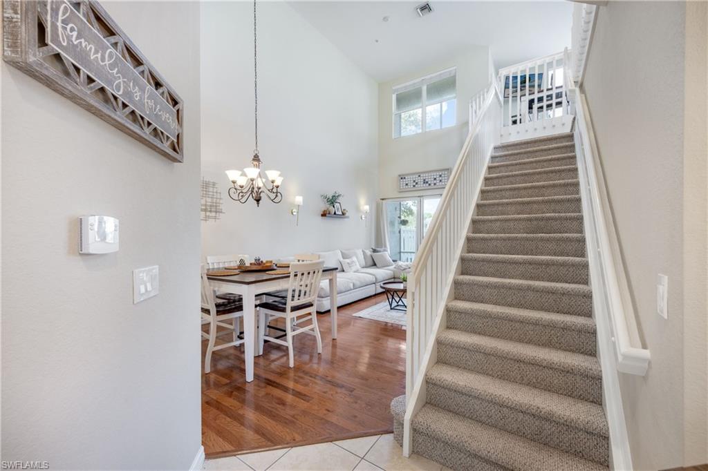Stairs with a towering ceiling, tile patterned flooring, and a chandelier