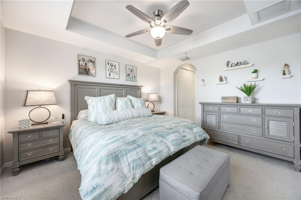Bedroom featuring a raised ceiling, carpet floors, ceiling fan, and a closet