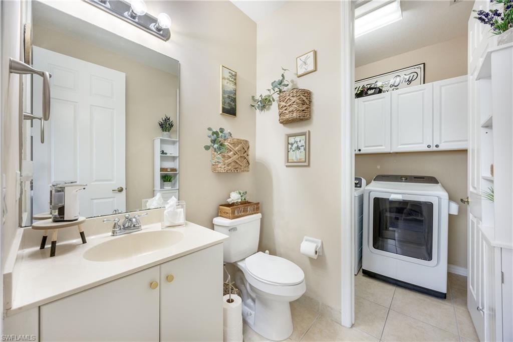 Half bath with vanity, independent washer and dryer, and light tile patterned flooring