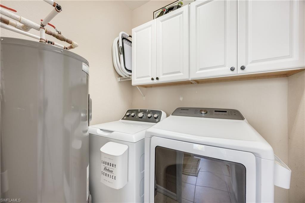 Laundry area featuring water heater, cabinet space, and washer and clothes dryer