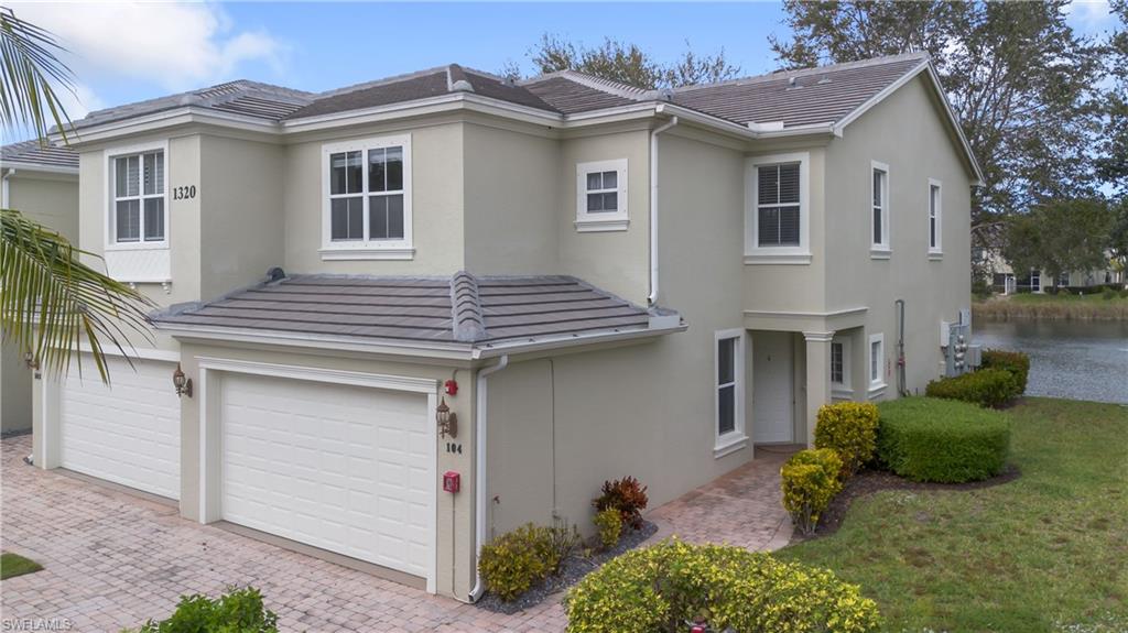 Contemporary-style house with stucco siding, an attached garage, decorative driveway, and a tiled roof
