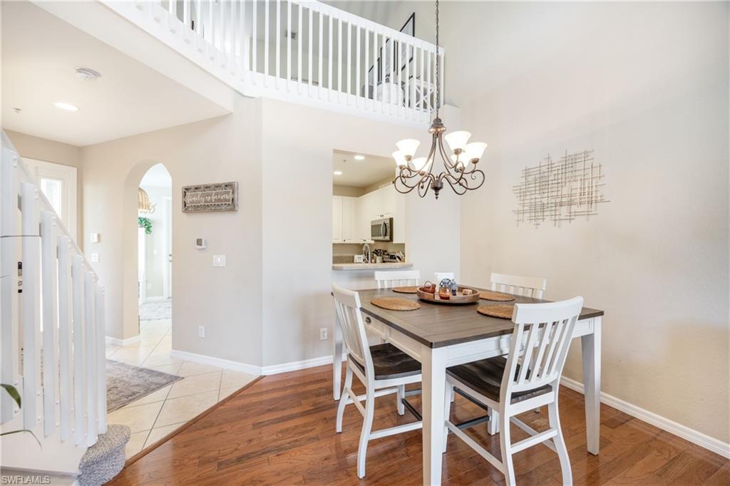 Dining space featuring light wood-style flooring, a towering ceiling, arched walkways, stairs, and a chandelier