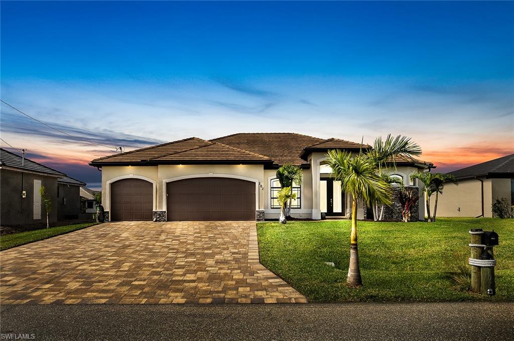 View of front of property featuring a 3 car garage and a well maintained lawn