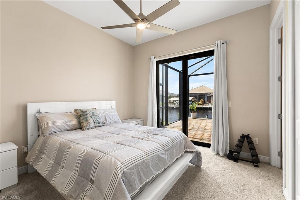 Guest bedroom (3) featuring access to outside, a water view, ceiling fan, and light carpet