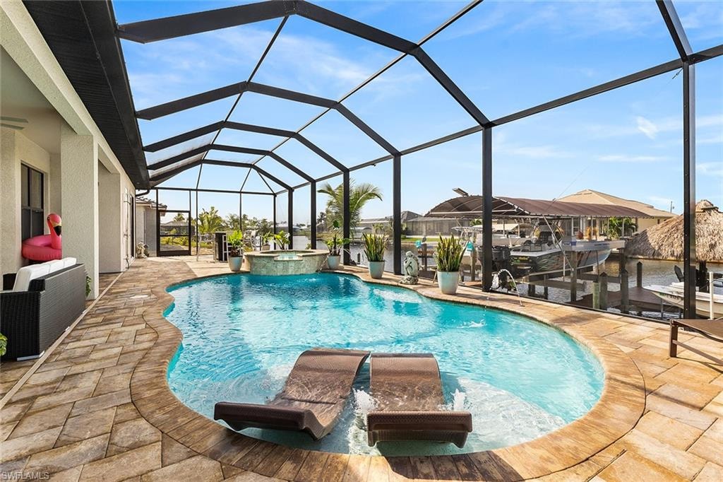 View of swimming pool with screened lanai, in ground custom hot tub, and pool water feature