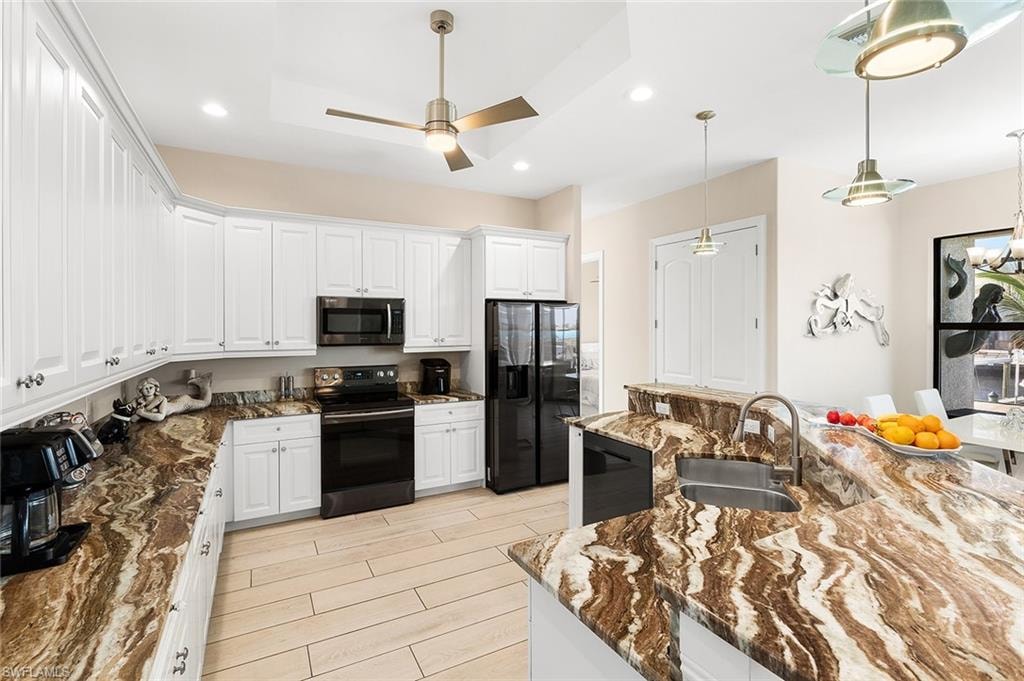 Kitchen with black appliances, white cabinets and granite countertops