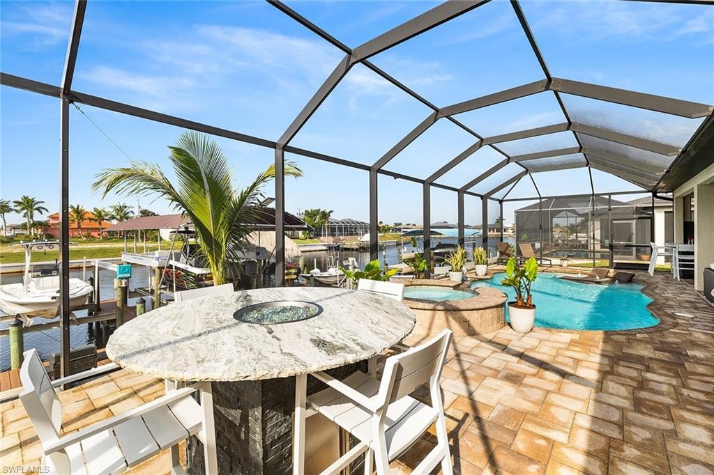 View of lanai with a custom bar top fire bowl, custom swimming pool with hot tub and west facing intersecting canal view