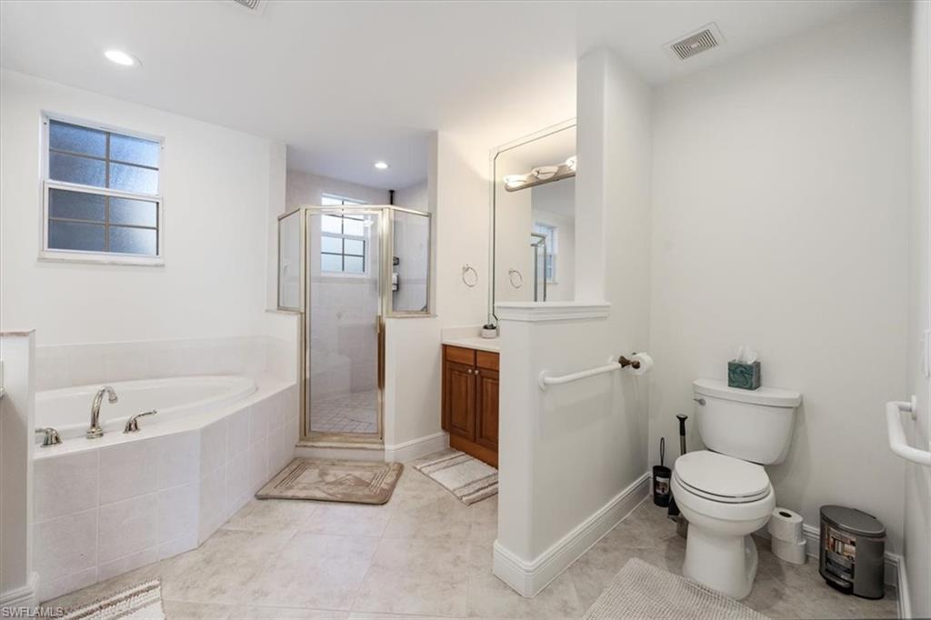 Full bath featuring a garden tub, vanity, a shower stall, light tile patterned flooring, and recessed lighting
