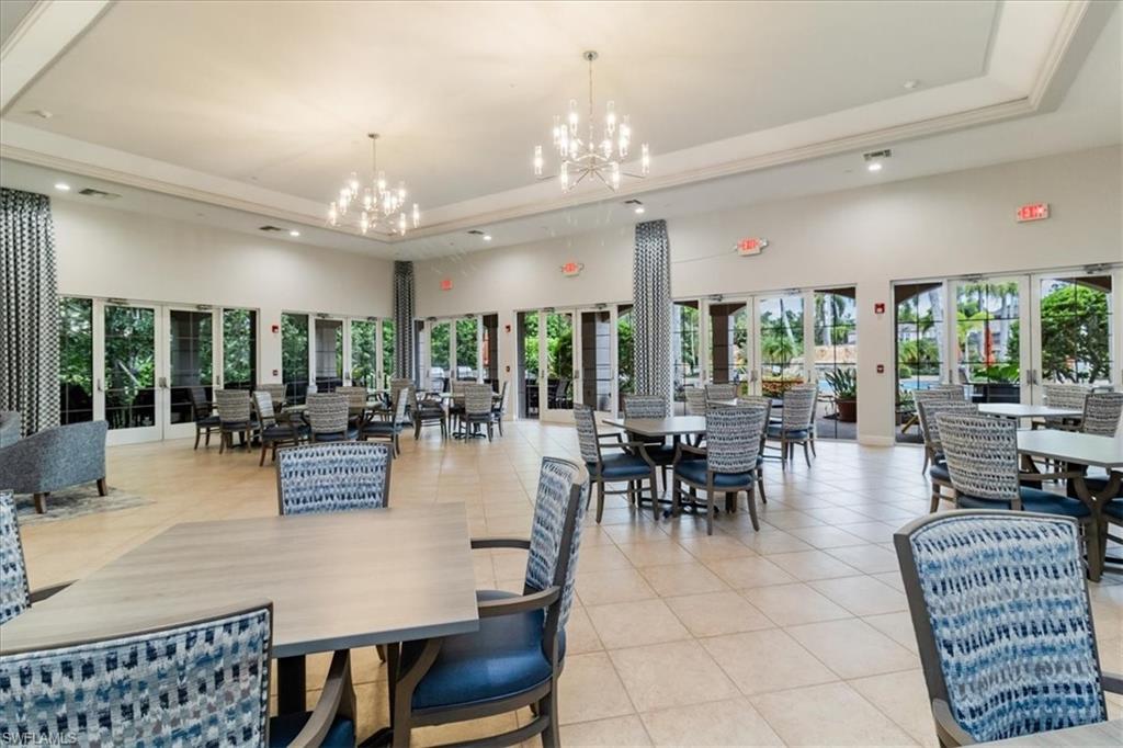 Dining room with a tray ceiling, a towering ceiling, light tile patterned floors, a chandelier, and recessed lighting