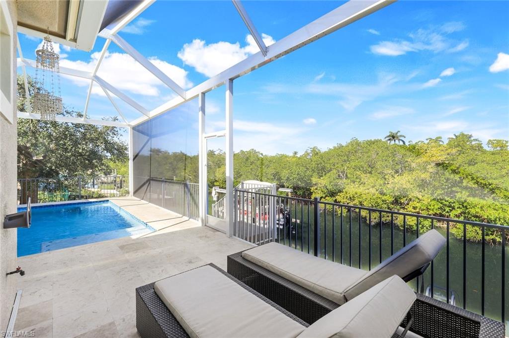 View of pool featuring a sunroom, glass enclosure, a patio area, and view of wooded area