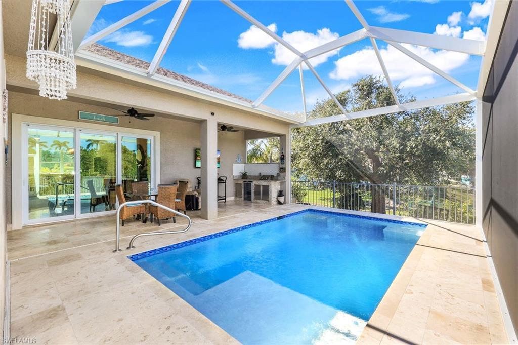 Swimming pool with a sunroom, a patio, ceiling fan, a lanai, and an outdoor kitchen