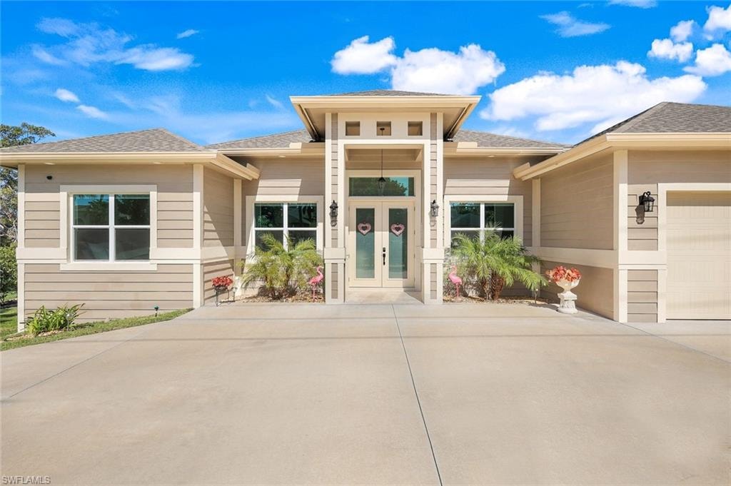 View of front of property featuring a shingled roof, driveway, and an attached garage