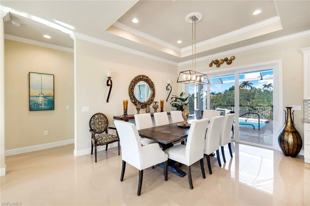 Dining room with a tray ceiling, light tile patterned floors, ornamental molding, and recessed lighting
