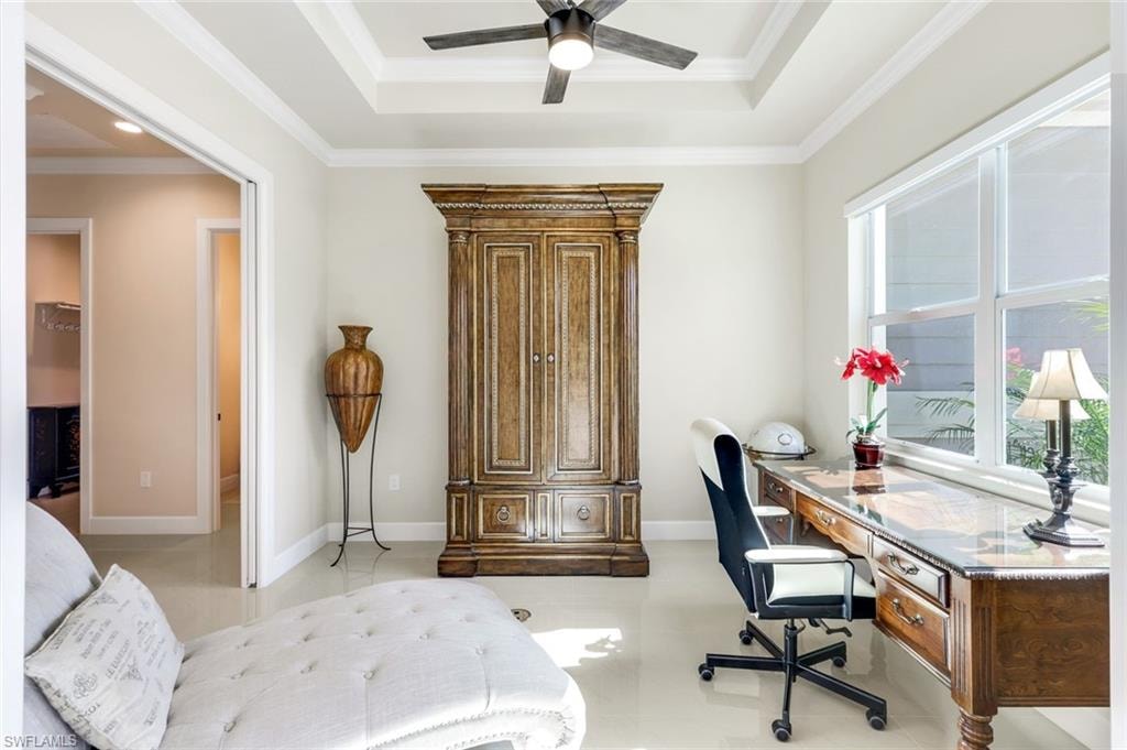 Office area featuring crown molding, a tray ceiling, light tile patterned flooring, and ceiling fan