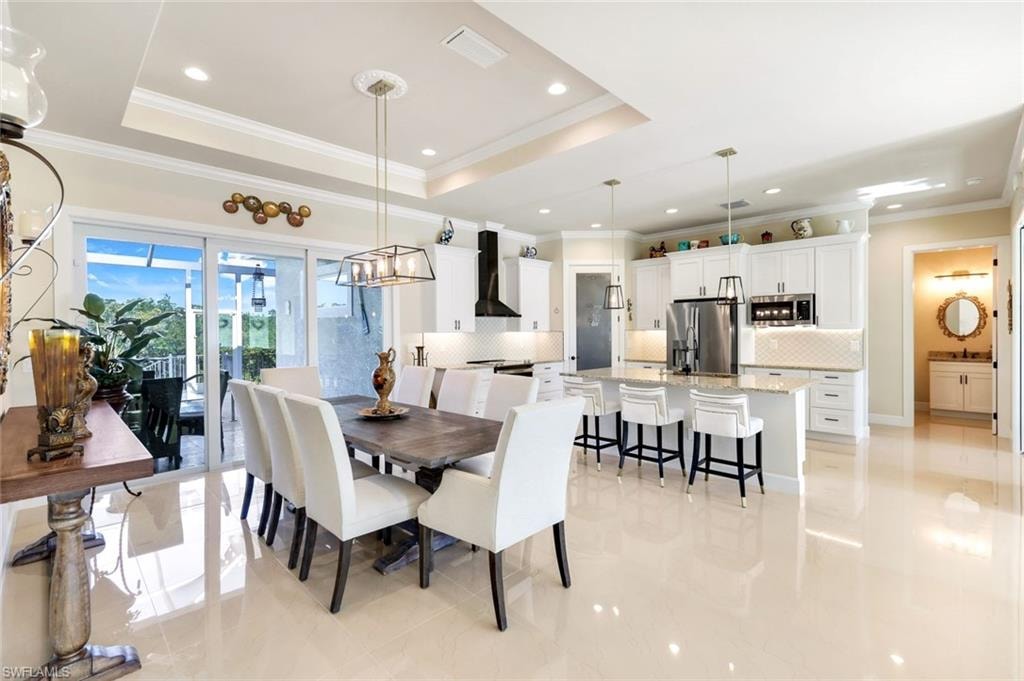 Dining space featuring a tray ceiling, ornamental molding, recessed lighting, and light tile patterned floors