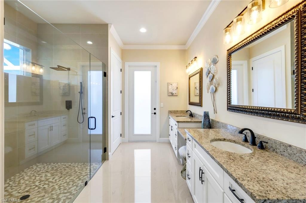 Bathroom with two vanities, a stall shower, ornamental molding, recessed lighting, and light tile patterned flooring