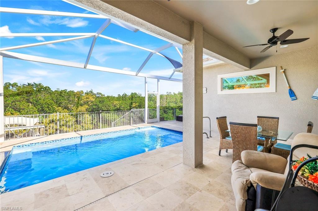 View of pool with a sunroom, a patio area, glass enclosure, a ceiling fan, and outdoor dining area