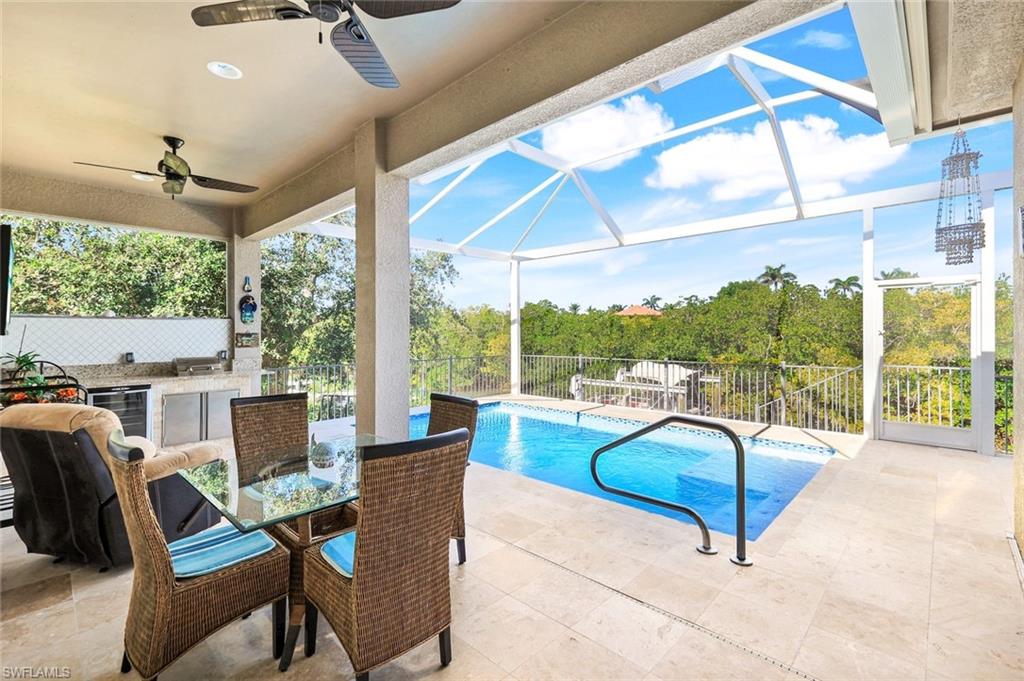 View of swimming pool with a sunroom, a lanai, exterior kitchen, a patio area, and a ceiling fan