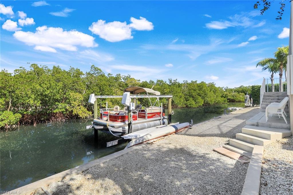 Dock area with a water view, view of wooded area, and boat lift