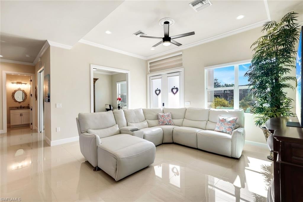 Living area with ornamental molding, a ceiling fan, and recessed lighting